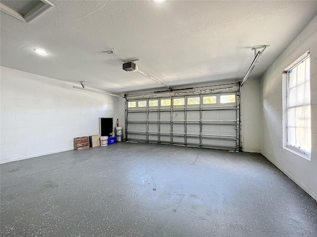 garage featuring concrete block wall and a garage door opener