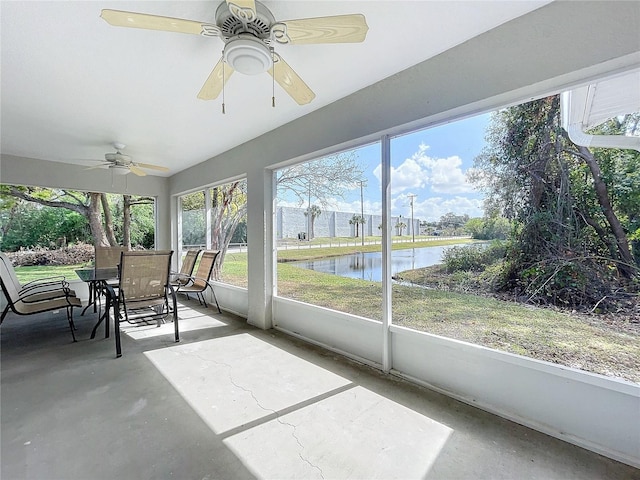 unfurnished sunroom with a ceiling fan and a water view