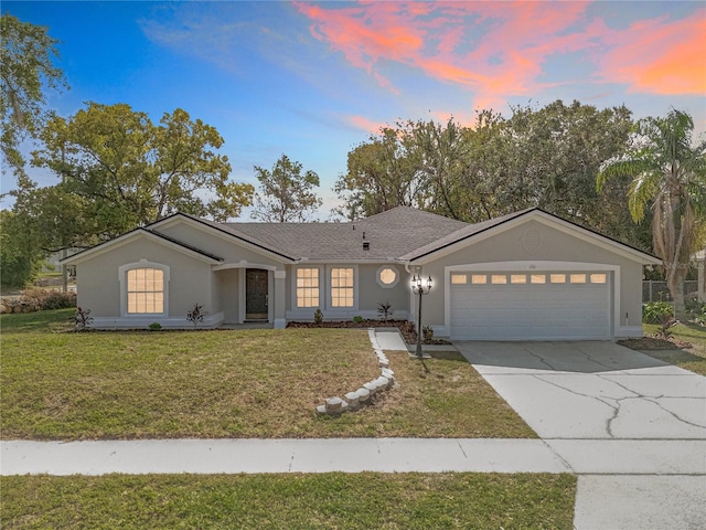 single story home with an attached garage, stucco siding, concrete driveway, and a yard