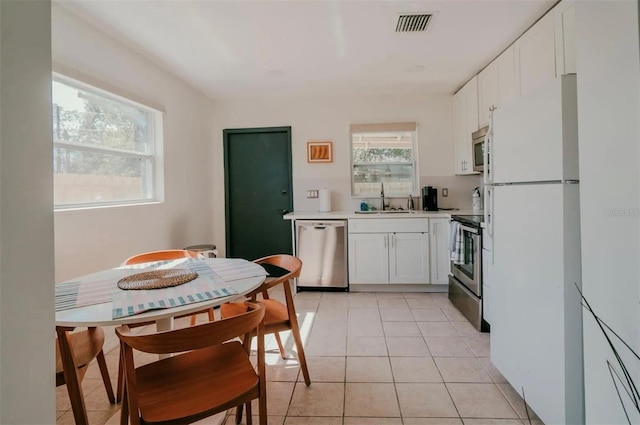 kitchen with white cabinetry, stainless steel appliances, sink, and light tile patterned floors