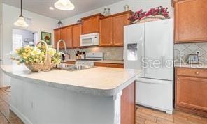 kitchen with backsplash, decorative light fixtures, white appliances, a center island with sink, and light wood-type flooring