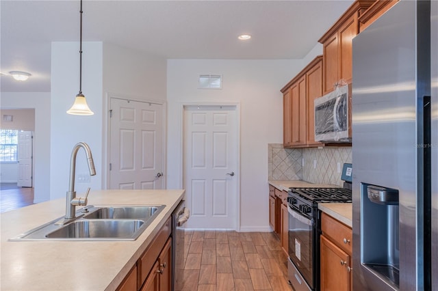 kitchen featuring sink, backsplash, decorative light fixtures, appliances with stainless steel finishes, and light wood-type flooring