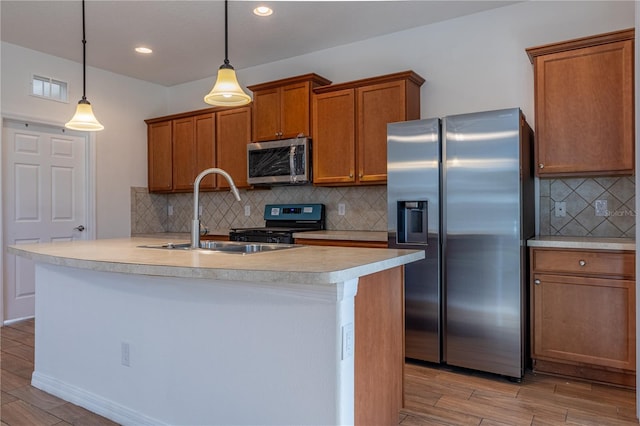 kitchen with sink, hanging light fixtures, appliances with stainless steel finishes, tasteful backsplash, and light hardwood / wood-style floors