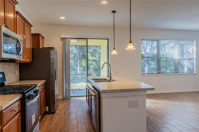 kitchen with a wealth of natural light, sink, a kitchen island with sink, and appliances with stainless steel finishes