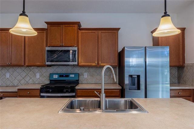 kitchen featuring decorative backsplash, appliances with stainless steel finishes, hanging light fixtures, and sink