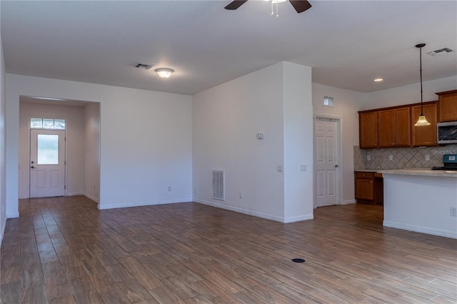 kitchen with backsplash, black range oven, hardwood / wood-style flooring, ceiling fan, and decorative light fixtures