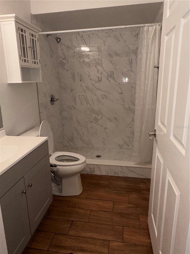 bathroom featuring hardwood / wood-style flooring, vanity, toilet, and walk in shower