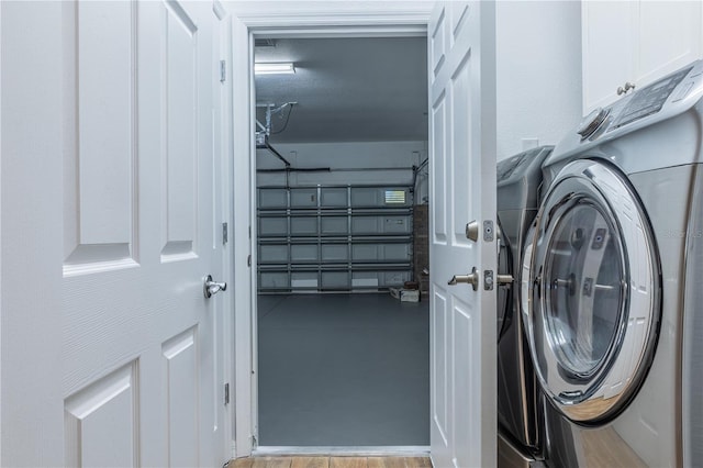 clothes washing area with cabinets, washer / dryer, and light wood-type flooring