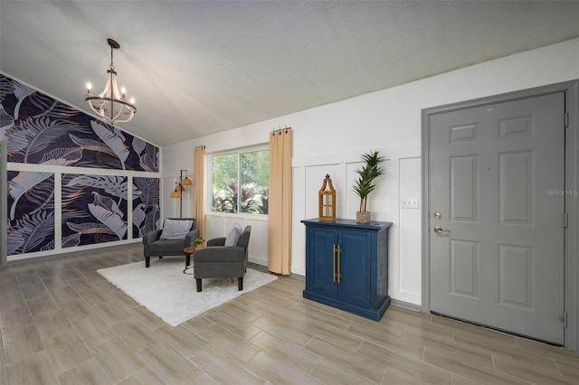 interior space featuring vaulted ceiling, light wood-type flooring, a textured ceiling, and a chandelier