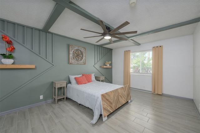 bedroom featuring ceiling fan, beamed ceiling, and a textured ceiling