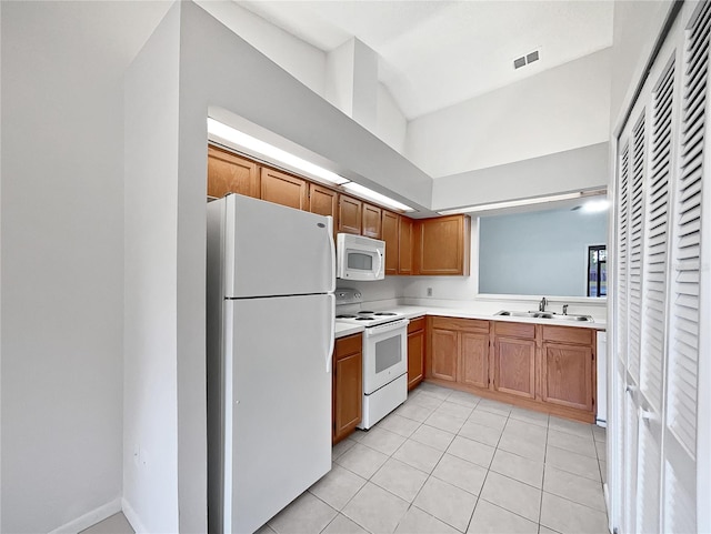 kitchen featuring white appliances, light tile patterned floors, and sink