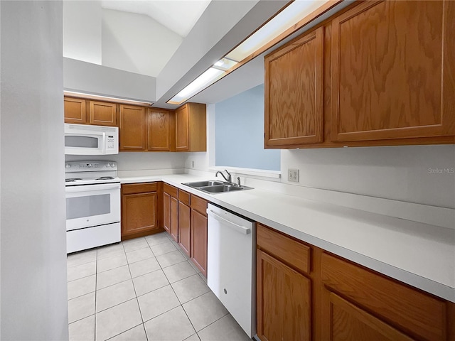 kitchen featuring lofted ceiling, sink, light tile patterned flooring, and white appliances