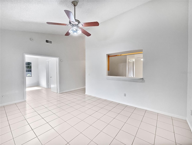 spare room featuring a textured ceiling, ceiling fan, light tile patterned floors, and vaulted ceiling