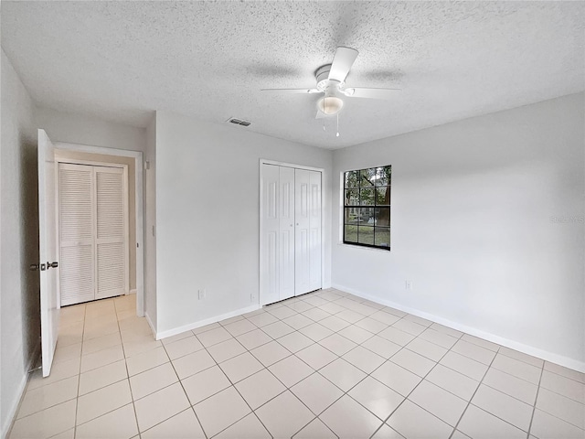 unfurnished bedroom featuring a closet, a textured ceiling, light tile patterned flooring, and ceiling fan