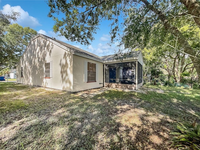 back of property with a sunroom and a lawn