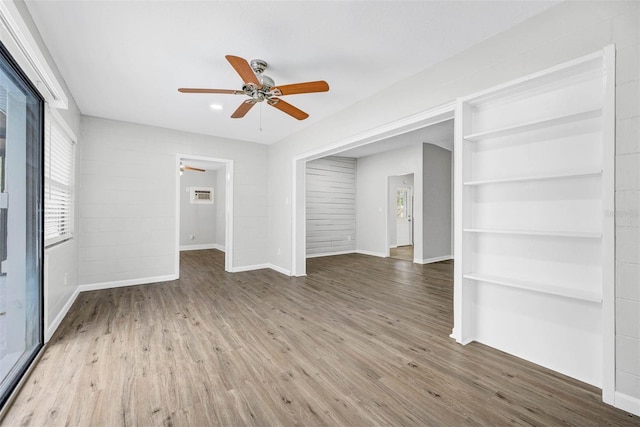 unfurnished living room featuring hardwood / wood-style floors, built in features, and ceiling fan