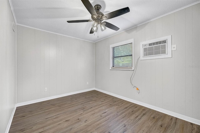 empty room featuring wood walls, dark hardwood / wood-style flooring, ceiling fan, a wall unit AC, and ornamental molding