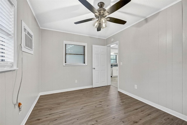 empty room with ornamental molding, dark wood-type flooring, wooden walls, and ceiling fan