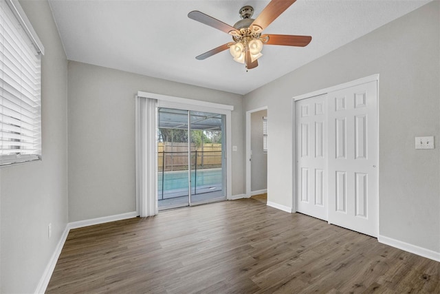 unfurnished bedroom with a closet, ceiling fan, dark hardwood / wood-style flooring, and access to exterior