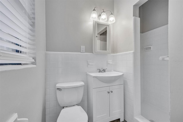 bathroom featuring vanity, toilet, tile walls, and a tile shower