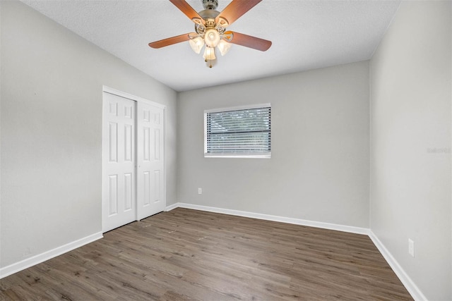 unfurnished bedroom featuring a closet, ceiling fan, a textured ceiling, and dark hardwood / wood-style flooring