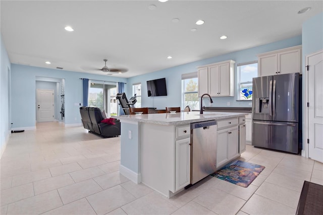 kitchen featuring a center island with sink, sink, ceiling fan, light tile patterned floors, and appliances with stainless steel finishes