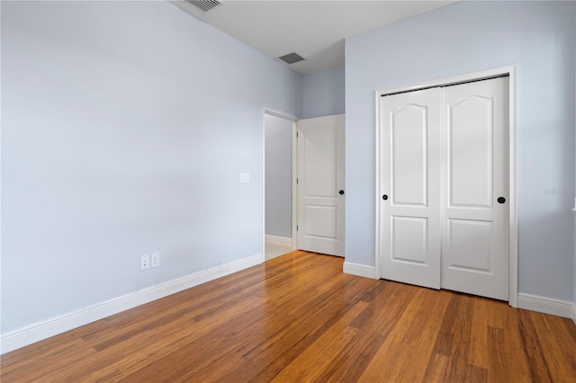 unfurnished bedroom featuring a closet and hardwood / wood-style floors