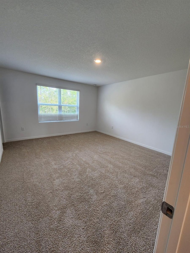 carpeted empty room featuring a textured ceiling