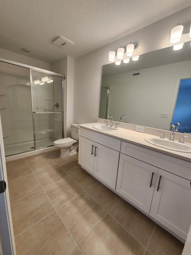 bathroom with a textured ceiling, walk in shower, toilet, vanity, and tile patterned flooring