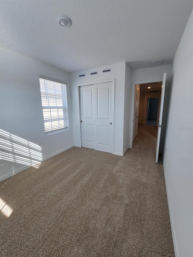 unfurnished bedroom featuring a textured ceiling, carpet flooring, and a closet