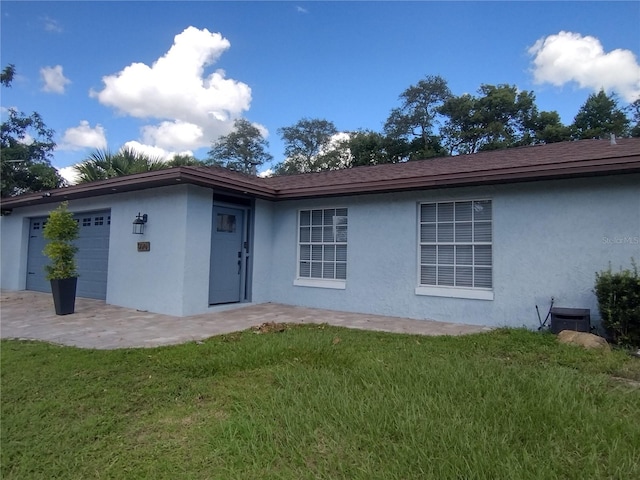 exterior space featuring a garage, cooling unit, and a lawn