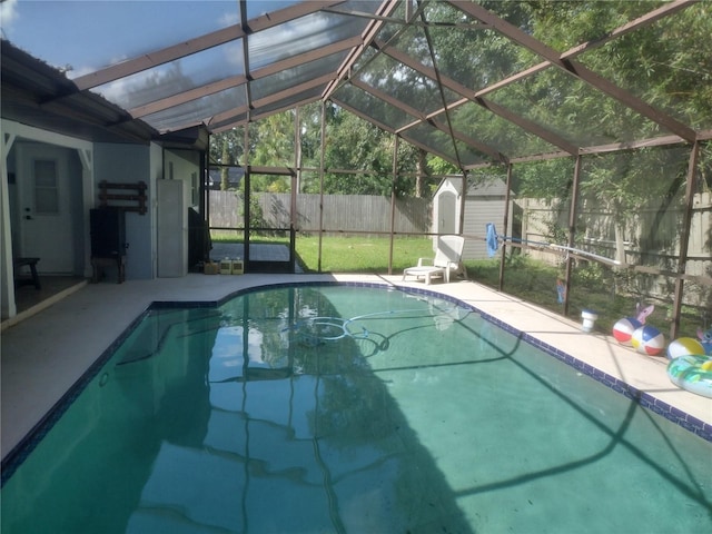 view of swimming pool featuring a storage shed, a patio, and a lanai