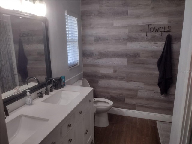 bathroom featuring vanity, toilet, hardwood / wood-style flooring, and wooden walls