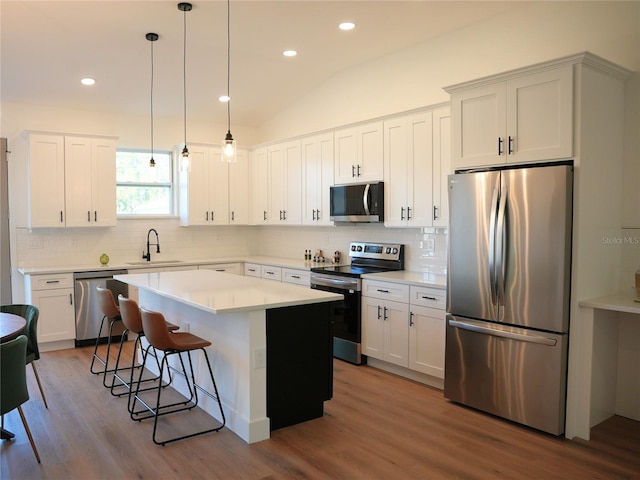 kitchen featuring sink, stainless steel appliances, a kitchen island, pendant lighting, and white cabinets