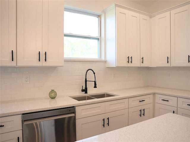 kitchen featuring stainless steel dishwasher, backsplash, white cabinetry, and sink