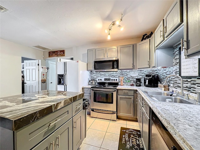 kitchen with tasteful backsplash, appliances with stainless steel finishes, sink, gray cabinets, and light tile patterned floors