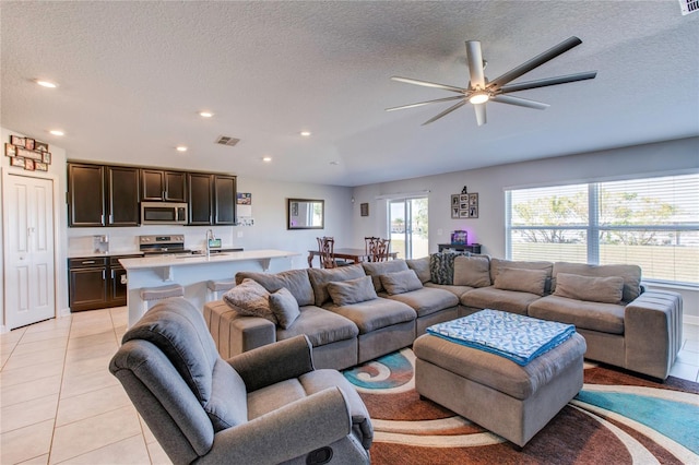 tiled living room featuring sink, a textured ceiling, and ceiling fan