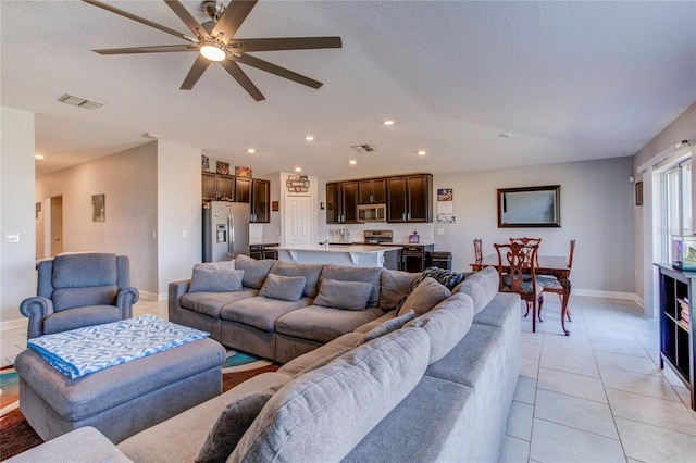 living room with a textured ceiling, light tile patterned floors, and ceiling fan