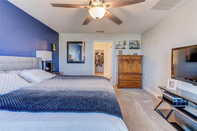 carpeted bedroom with a closet, a textured ceiling, a spacious closet, and ceiling fan