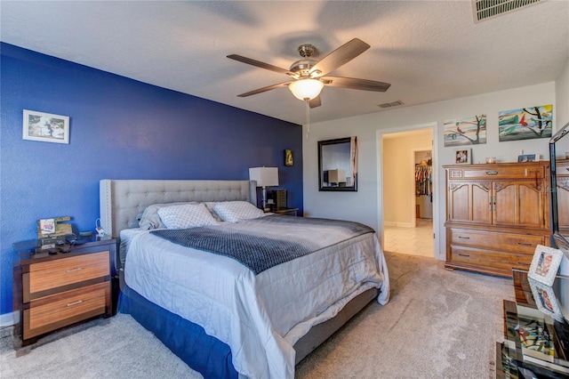 bedroom with a textured ceiling, light colored carpet, and ceiling fan