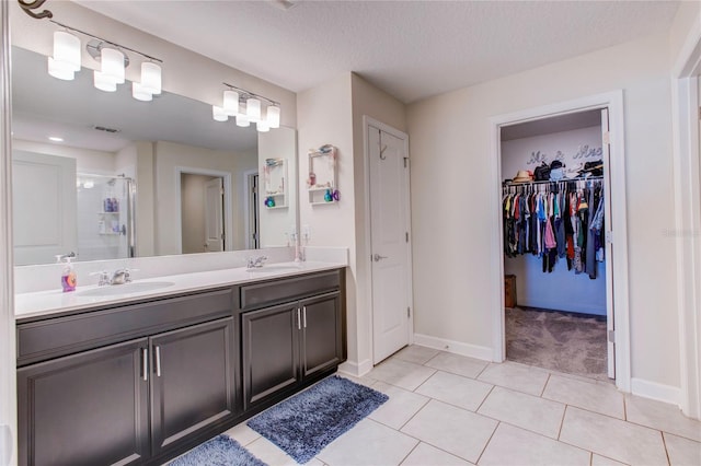 bathroom with a shower with door, tile patterned floors, a textured ceiling, and vanity