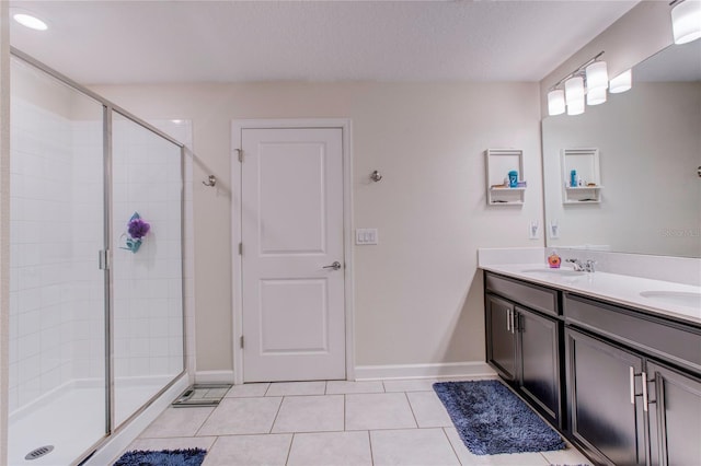 bathroom featuring vanity, a shower with shower door, a textured ceiling, and tile patterned flooring