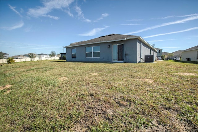 rear view of house featuring a lawn and central AC unit