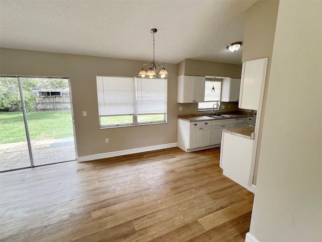 kitchen featuring sink, white cabinetry, light wood-type flooring, and a healthy amount of sunlight