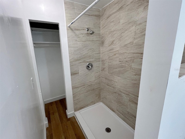 bathroom with a tile shower and wood-type flooring