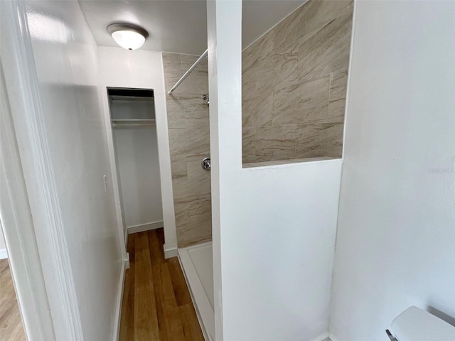 bathroom with toilet, tiled shower, and hardwood / wood-style floors