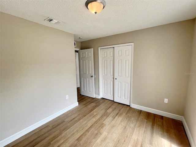 unfurnished bedroom with a closet, a textured ceiling, and light wood-type flooring