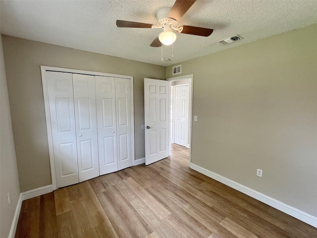 unfurnished bedroom featuring light hardwood / wood-style flooring, a textured ceiling, a closet, and ceiling fan