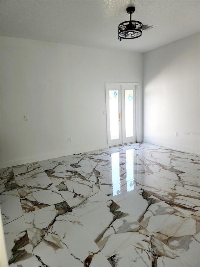 spare room featuring french doors and a textured ceiling