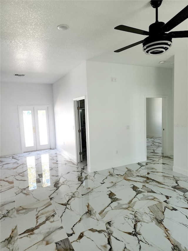 empty room featuring french doors, ceiling fan, and a textured ceiling